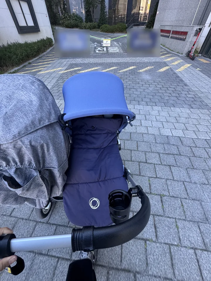 아파트 단지 길을 가는 쌍둥이 유모차를 뒤에서 본 모습. 오른쪽 칸 네이비 풋머프에 부가부 로고(배경 표지판은 흐리게 처리)