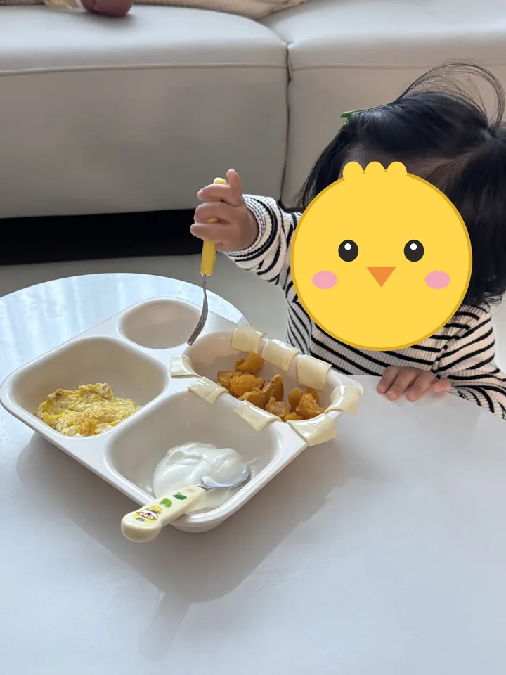 식판의 계란·고구마·요거트를 포크로 먹는 첫째(얼굴은 병아리 그림으로 가림)